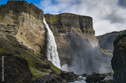 Massive waterfall with mist surrounded by green moss