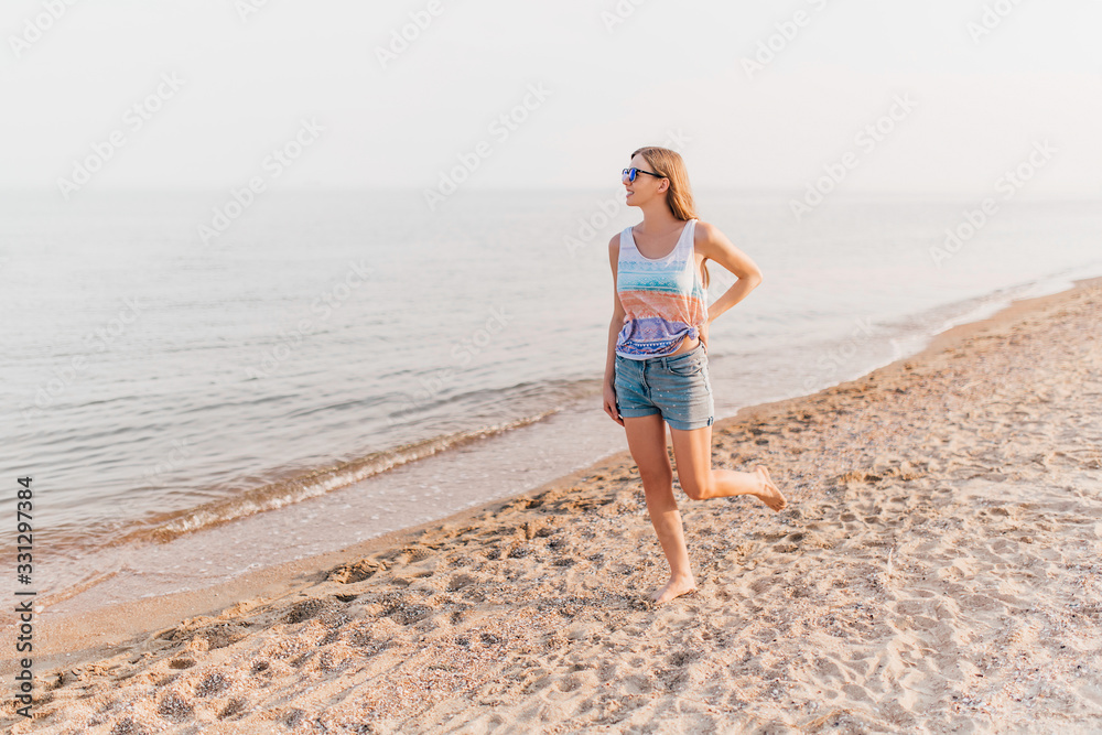 Young girl strolling along the beach enjoying the Sunny weather