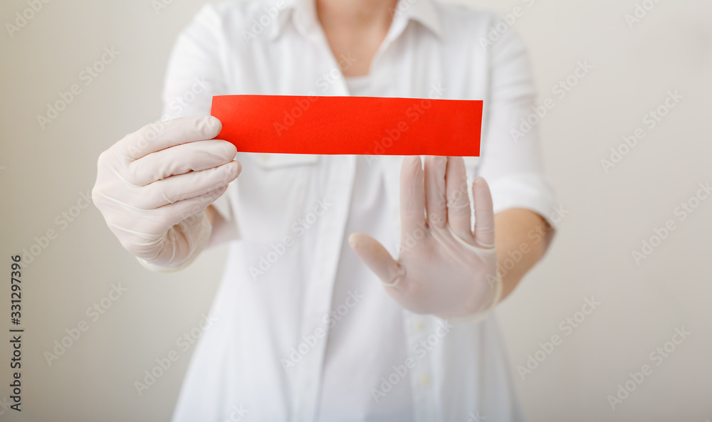 Doctor in a hospital holding a red warning sign mock up for your text. Doctor show stop hands gesture for stop virus or disease. Doctor hands in white coat, gloves. Concept of healthcare and medicine