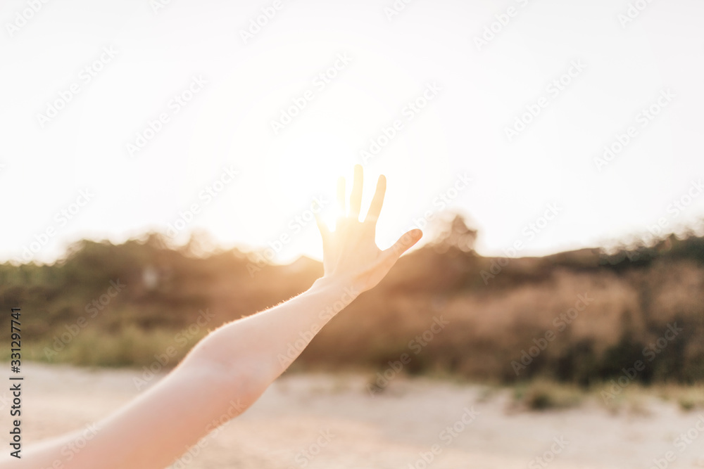 the girl holding out her hand to the sky covers the Sun with her hand while standing on the beach the girl holding out her hand to the sky covers the Sun with her hand while standing on the beach