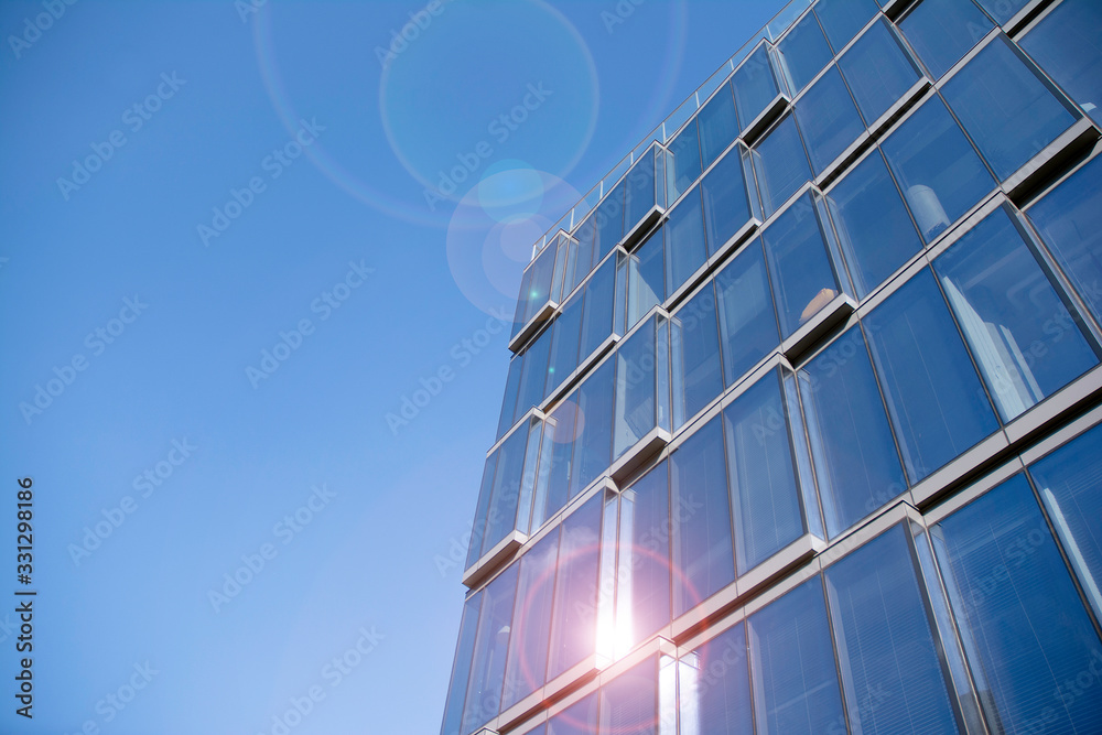 Office building glass facades on a bright sunny day with sunbeams in the blue sky. Office building glass facades on a bright sunny day with sunbeams in the blue sky.