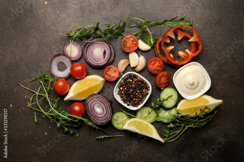 Set of sliced vegetables and spices for the preparation of salads or other dishes on a dark table. top view.