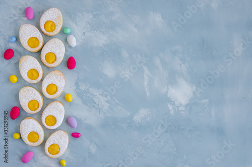 Homemade Easter cookies in the form of Easter egg with powdered sugar and lemon cream on a light blue concrete background. A greeting card. Easter background. Horizontal  Copy space. Top view