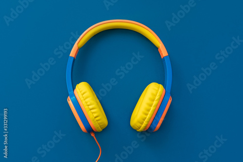 Multi-colored headphones on blue background. Minimalistic fashion music concept. Trendy color of the year concept. Top view, flat lay, copy space