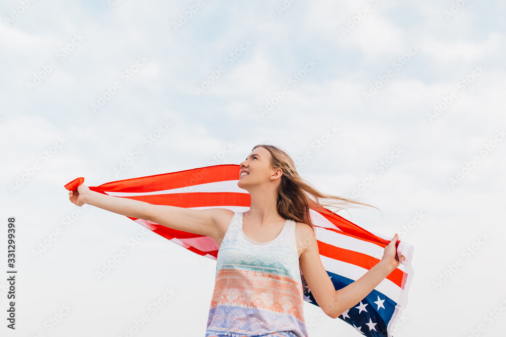 woman with an American flag in her outstretched hands standing on the beach woman with an American flag in her outstretched hands standing on the beach
