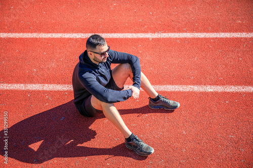 Athletes walk and stretch on the red wet track of athletics, which is a rubber artificial track for run and field athletes.