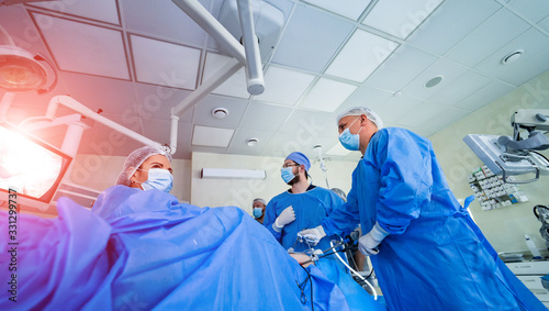 Group of doctors perform an operation to a patient. Surgeons in medical uniform and masks working in the operating room