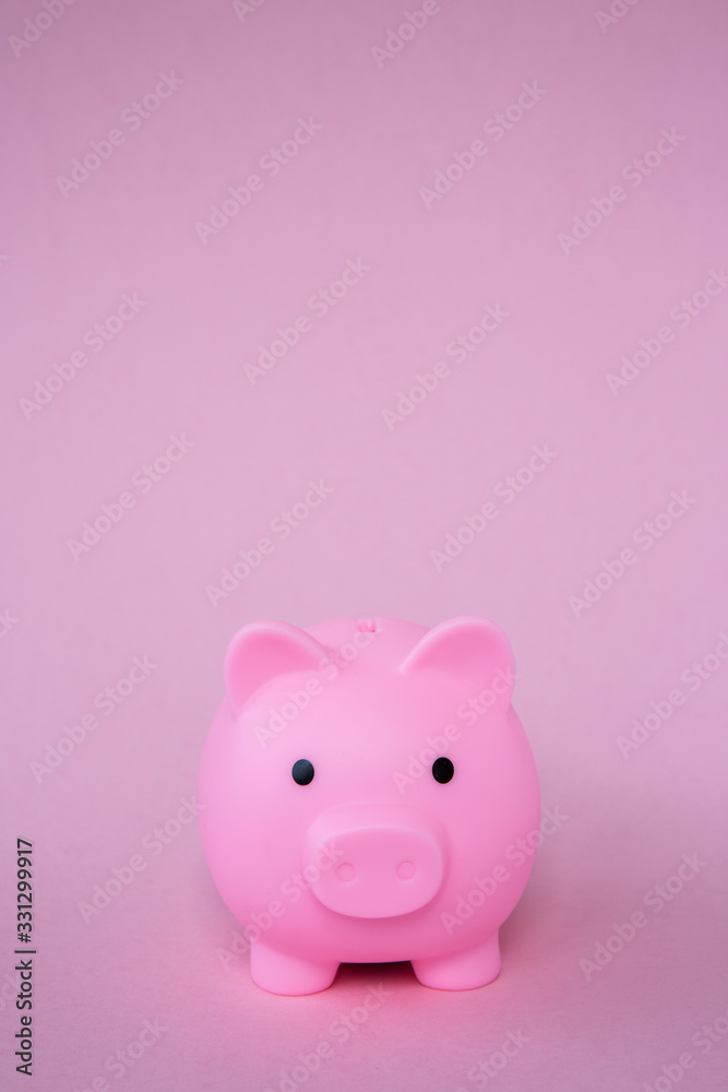 A pink childrens piggy bank on a pink background with copy space