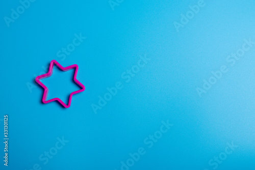 Pick plastic cookie cutter for making cookies in the shape of a star on a blue background. Culinary concept. Flat lay with copyspace.