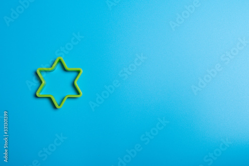 Green plastic cookie cutter for making cookies in the shape of a star on a blue background. Culinary concept. Flat lay with copyspace.