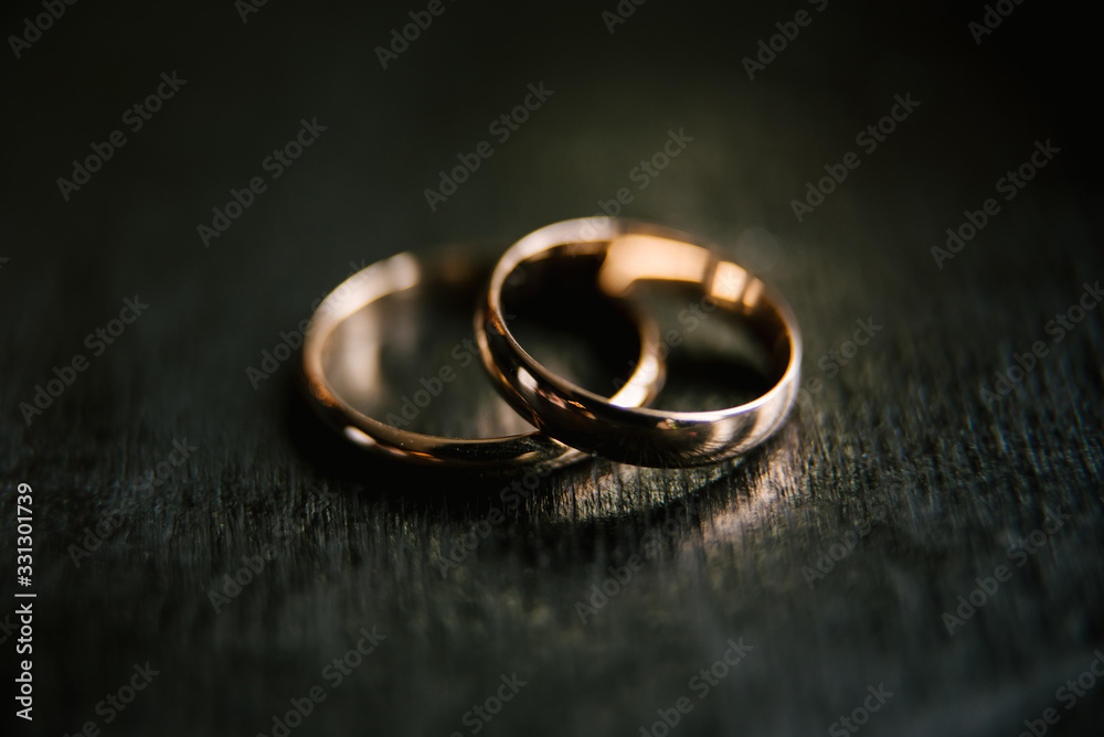 Elegant wedding rings for the bride and groom on a black background with highlights, macro, selective focus Elegant wedding rings for the bride and groom on a black background with highlights, macro, selective focus