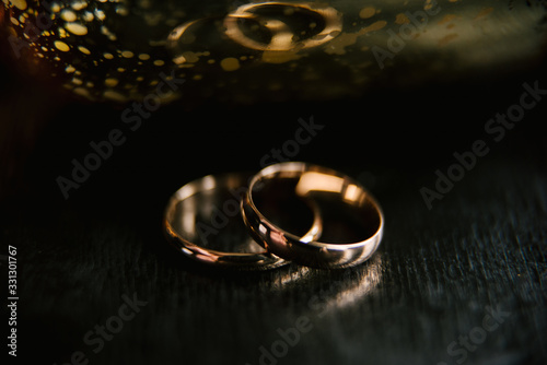 Elegant wedding rings for the bride and groom on a black background with highlights, macro, selective focus