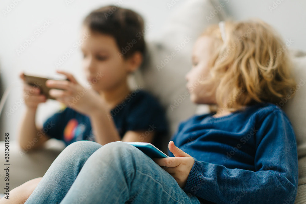 2 children a boy and a girl sit on gadgets and play phones .Homeschooling concept, modern kids and programming learning 2 children a boy and a girl sit on gadgets and play phones .Homeschooling concept, modern kids and programming learning