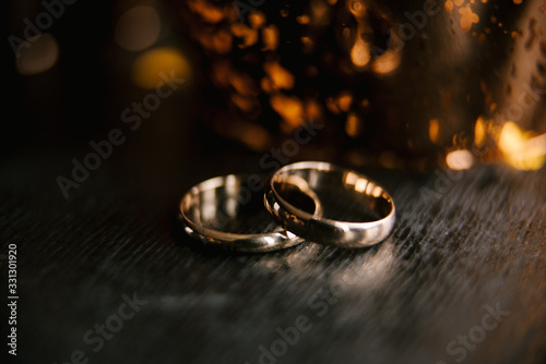 Elegant wedding rings for the bride and groom on a black background with highlights, macro, selective focus