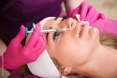 Beautician doctor hands doing beauty procedure to female lips with syringe. Cosmetic medicine and surgery, beauty injections concept