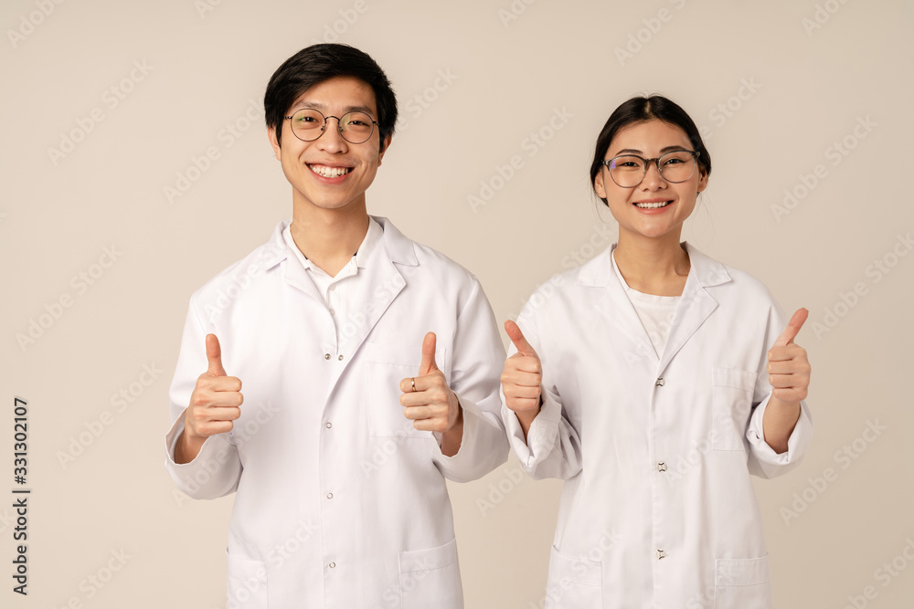 Image of asian young medical doctors in white uniform gesturing thumbs up Image of asian young medical doctors in white uniform gesturing thumbs up