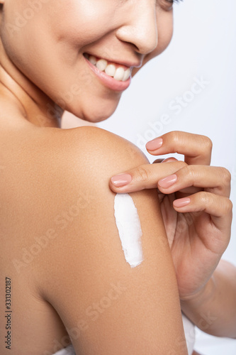 Happy pretty woman is applying arm cream