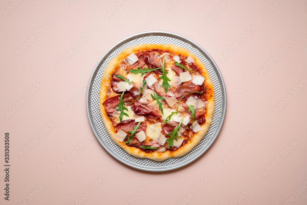 Pizza prosciutto on a baking tray. Whole ham pizza with arugula Pizza prosciutto on a baking tray. Whole ham pizza with arugula