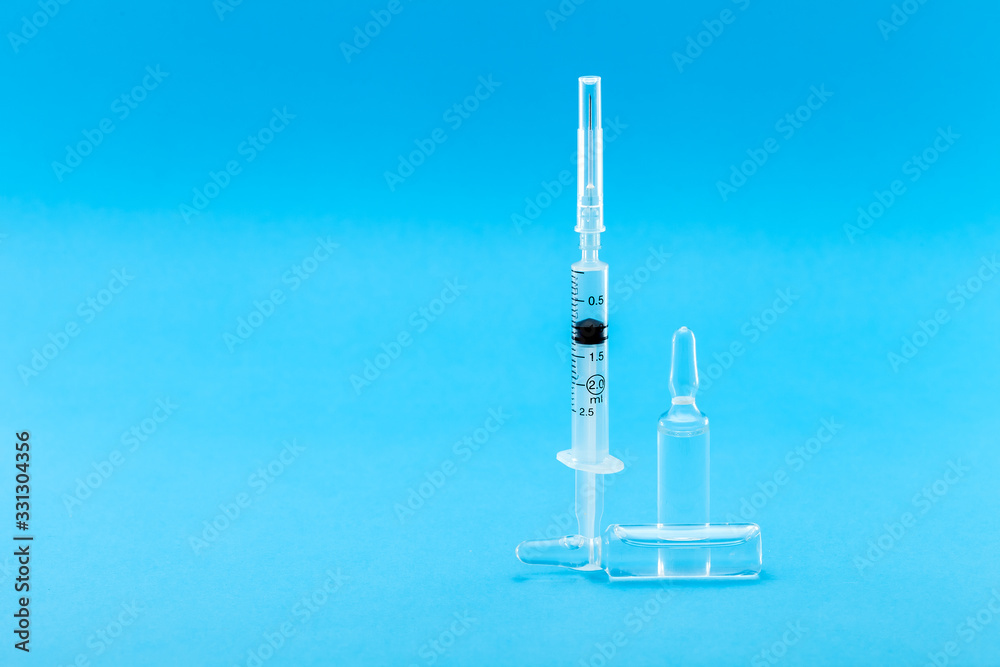 syringe with a vaccine in a glass ampoule on a blue background with a copy space. syringe with a vaccine in a glass ampoule on a blue background with a copy space.