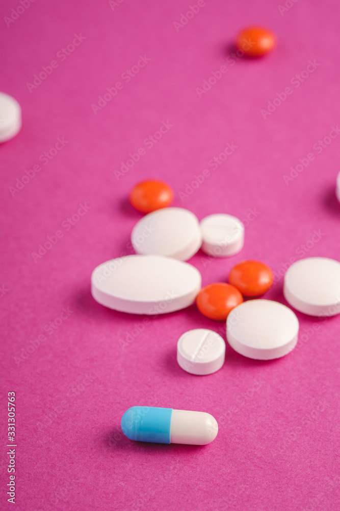 Pills and tablets on bright pink purple background, healthcare medical concept, antibiotics and cure, angle view Pills and tablets on bright pink purple background, healthcare medical concept, antibiotics and cure, angle view