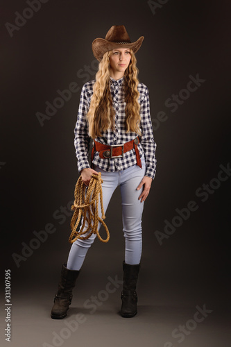 Lovely blonde posing in studio with a cowboy hat and a rope.