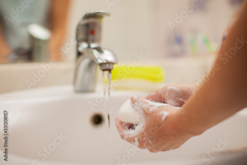 Woman washing hands with soap in bathroom. People and healthcare concept.