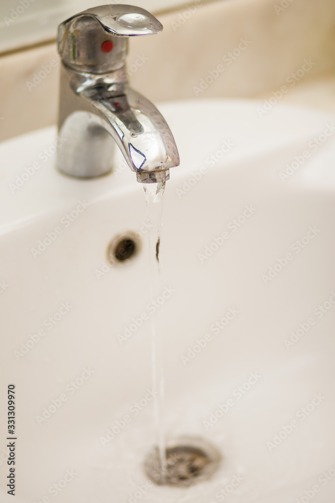 Water tap faucet with flowing water in a bathroom sink.. Water tap faucet with flowing water in a bathroom sink..