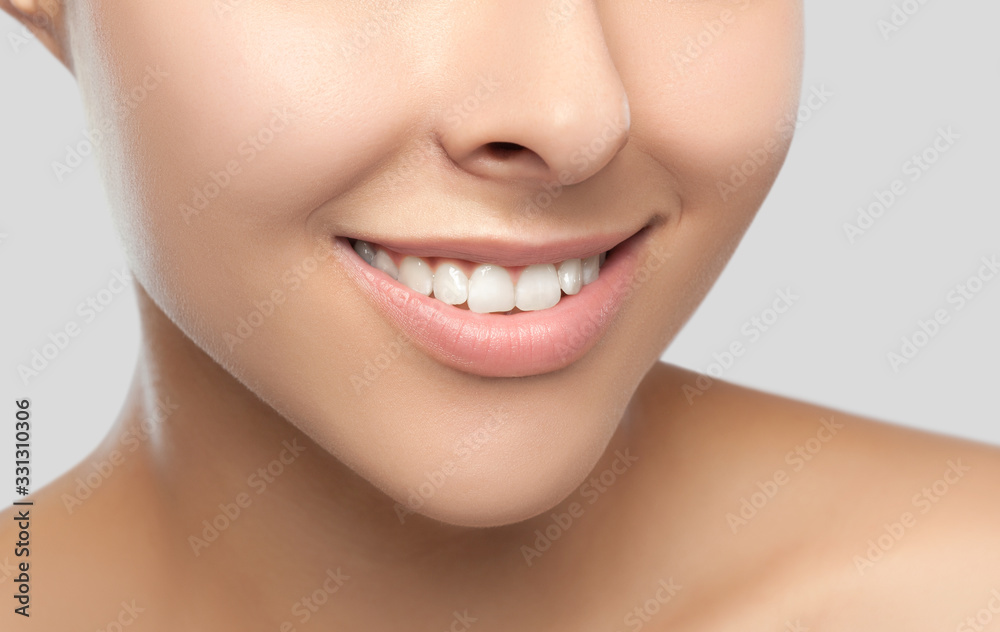 Portrait of a beautiful happy woman with a beautiful smile, clean and healthy skin and nude makeup on a gray background. Cosmetology skin care and makeup. Smile close up. Portrait of a beautiful happy woman with a beautiful smile, clean and healthy skin and nude makeup on a gray background. Cosmetology skin care and makeup. Smile close up.