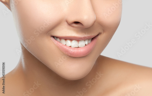 Portrait of a beautiful happy woman with a beautiful smile, clean and healthy skin and nude makeup on a gray background. Cosmetology skin care and makeup. Smile close up.