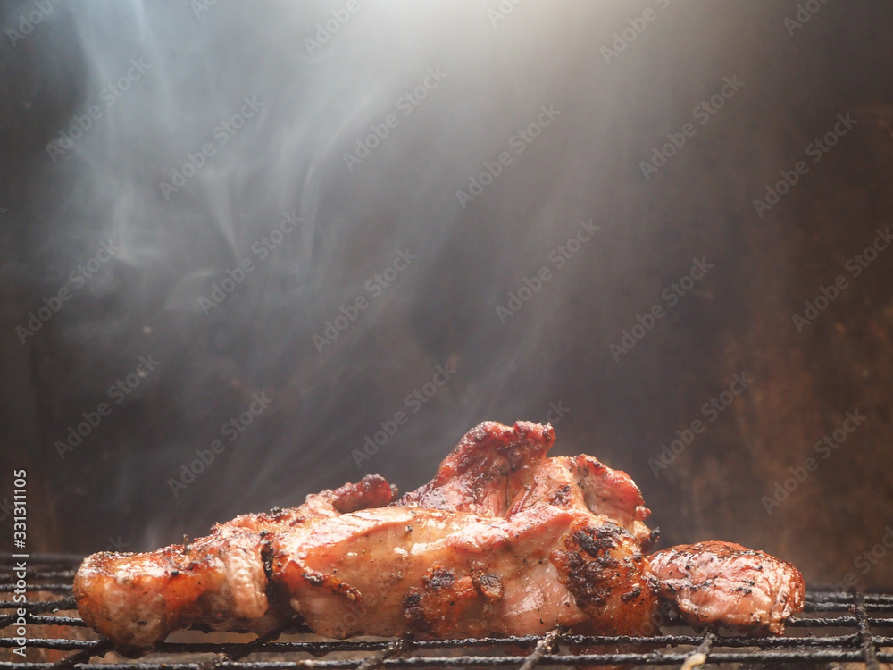 Foto de Grilled pork meat is burning on the grilling basket with tongs on the charcoal grill