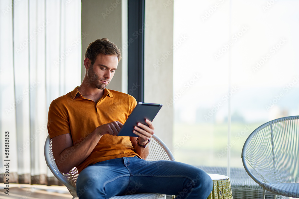 Young man using a digital tablet at home Young man using a digital tablet at home