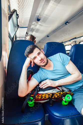 young pretty modern hipster guy traveller on train with skateboard alone, lifestyle vacation people concept