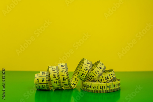 yellow measuring   tape  on green and yellow background photo