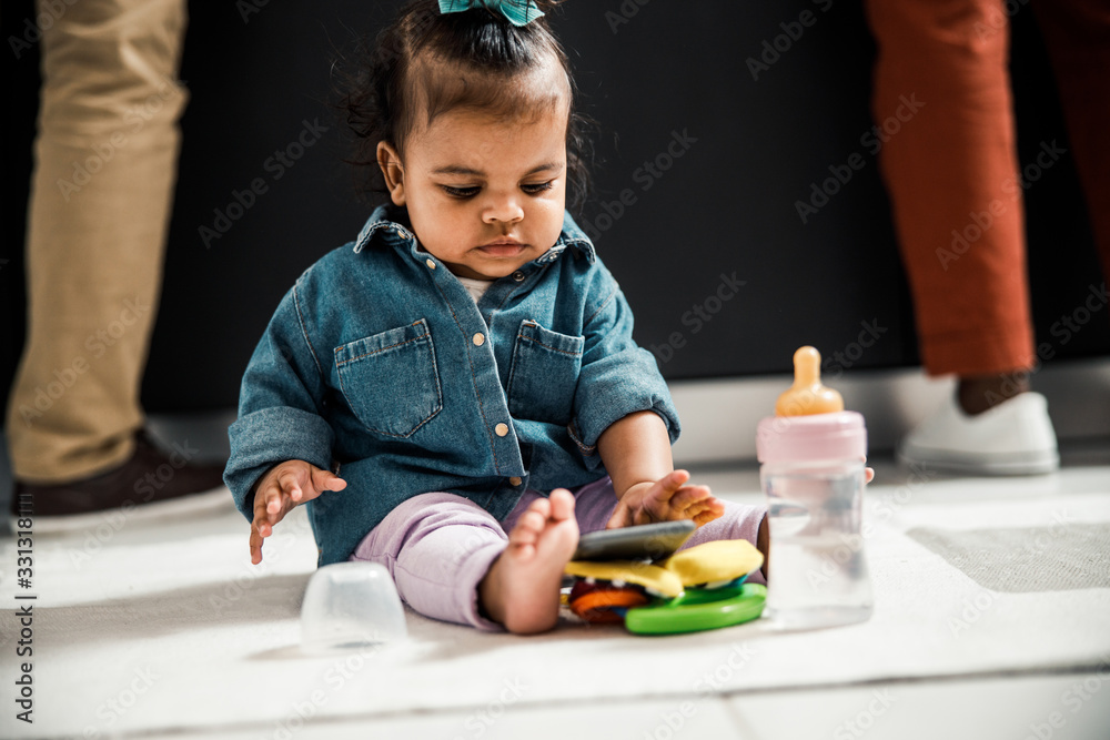 Adorable Afro American toddler sitting on the floor at home Adorable Afro American toddler sitting on the floor at home