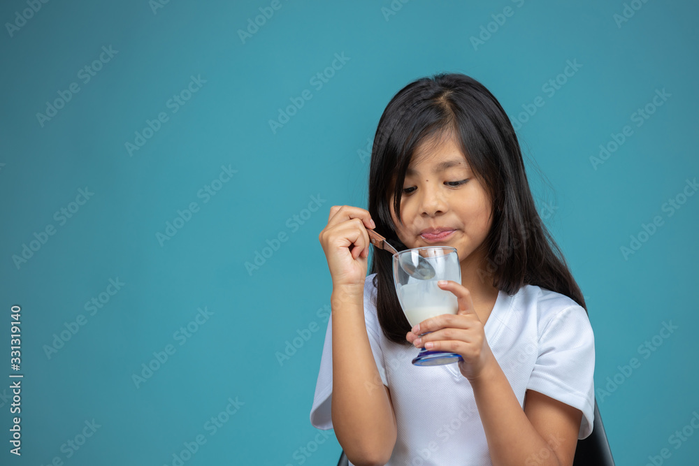 girl eating a glass of yogurt on blue background girl eating a glass of yogurt on blue background