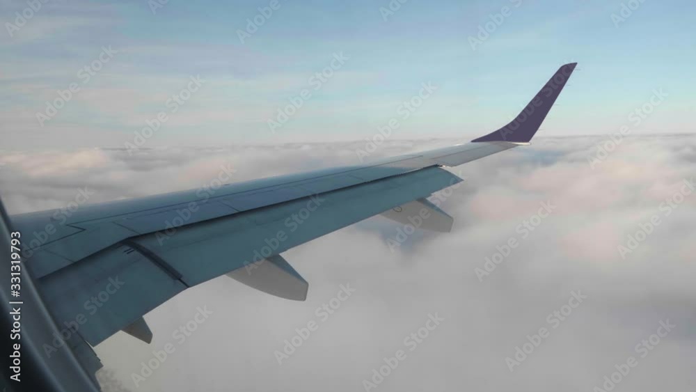 View from porthole on clouds under wing of flying aircraft. Plane lays roll View from porthole on clouds under wing of flying aircraft. Plane lays roll