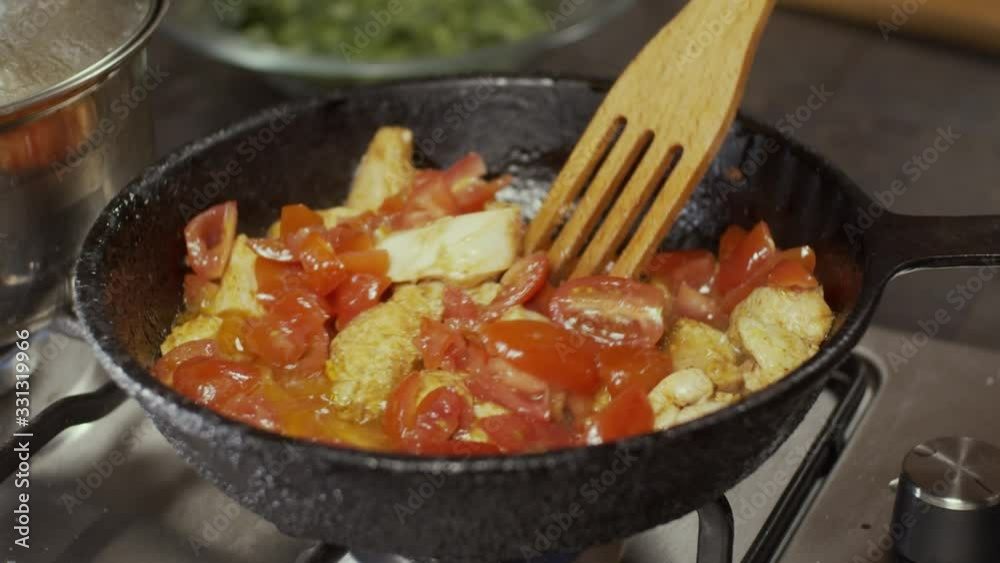 Adding cherry tomatoes in chicken meat in frying pan, shallow depth of field, slow motion Adding cherry tomatoes in chicken meat in frying pan, shallow depth of field, slow motion