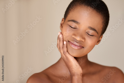 Young woman smiling while touching her soft cheek