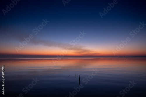 purplish-orange sunset over the water, calm, night