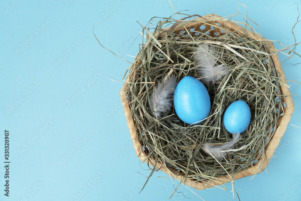 Two blue eggs in the wicker basket on the blue background. Copy space. Place for text and design. Happy Easter. Top view. Flat layout. Two blue eggs in the wicker basket on the blue background. Copy space. Place for text and design. Happy Easter. Top view. Flat layout.