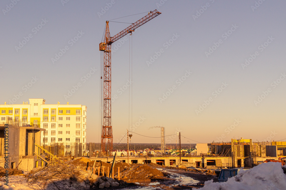 on a spring evening, a tower crane builds buildings on the outskirts of the city on a spring evening, a tower crane builds buildings on the outskirts of the city