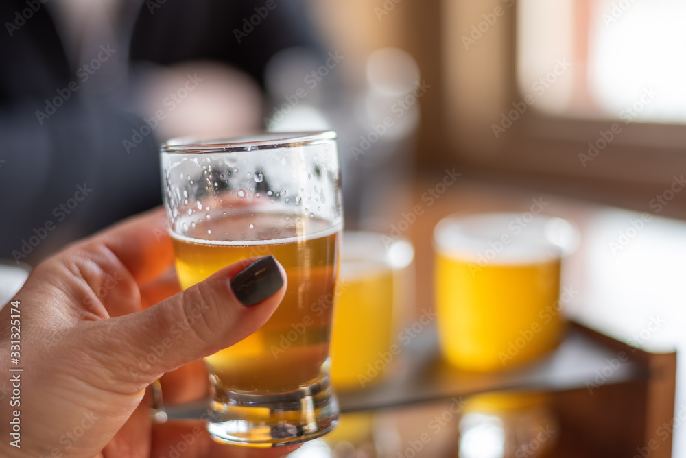 Closeup of a woman sampling craft beer from a flight