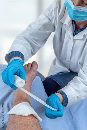 Wounded man's leg hurts. Patient receiving a first aid. Nurse bandaging a wound.