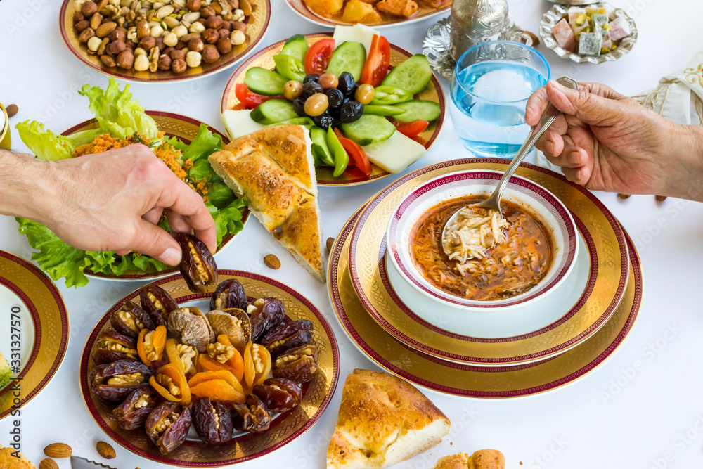 Hands take dry date fruit and soup on Traditional Ramadan Dinner-Iftar Table.