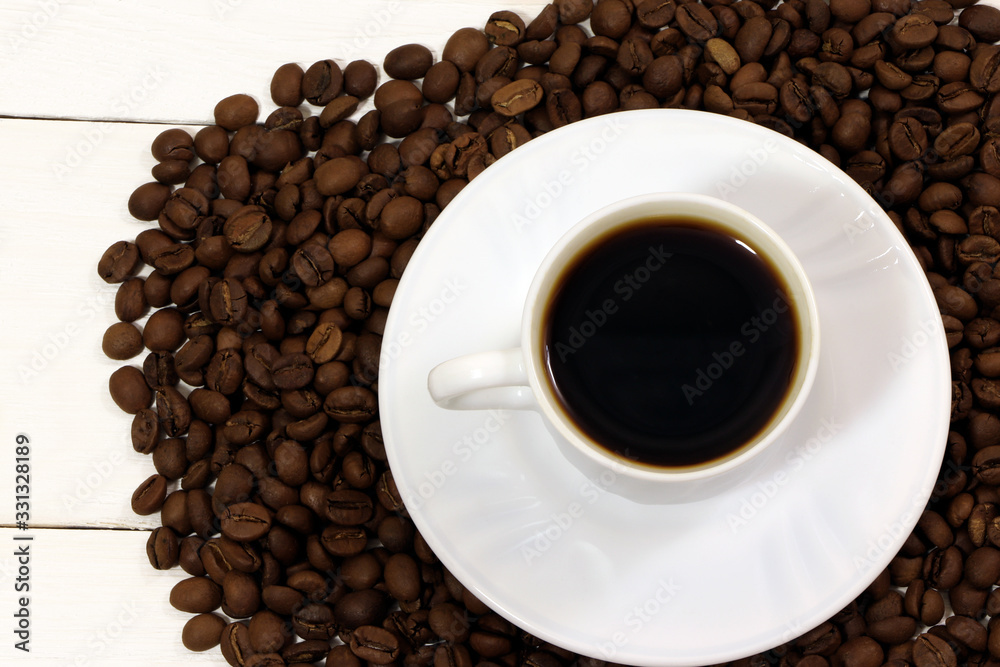 Fototapeta premium A white cup of coffee and coffee beans on a wooden table.