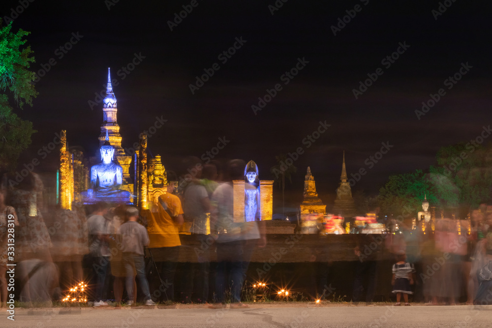 Old Buddhist architecture and people blurred at night.