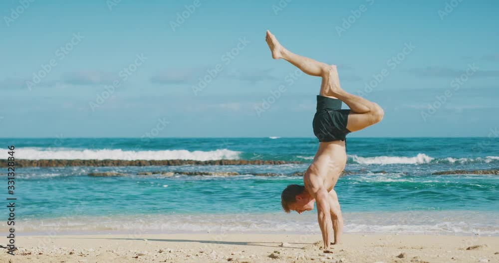 Strong flexible man balancing in a handstand on the beach in the morning, balance and strength workout Strong flexible man balancing in a handstand on the beach in the morning, balance and strength workout