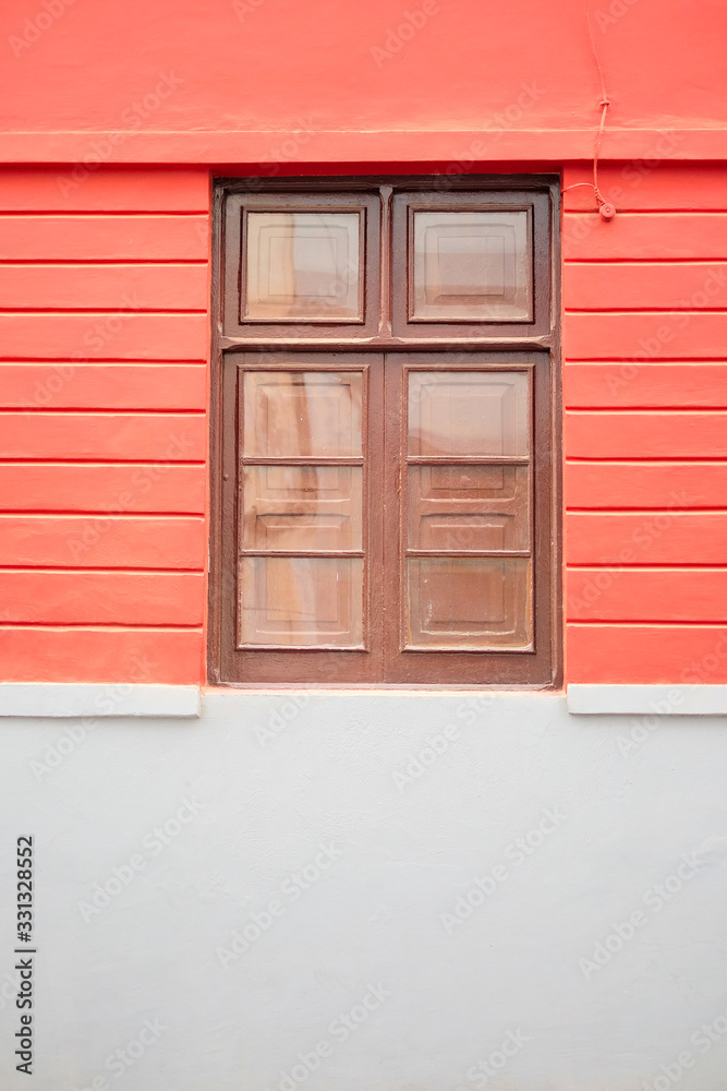 Simple brown wooden window in a coral pink wall.