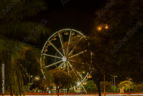 Long exposure of colorful ferris wheel and light trails on the expressway road at night.