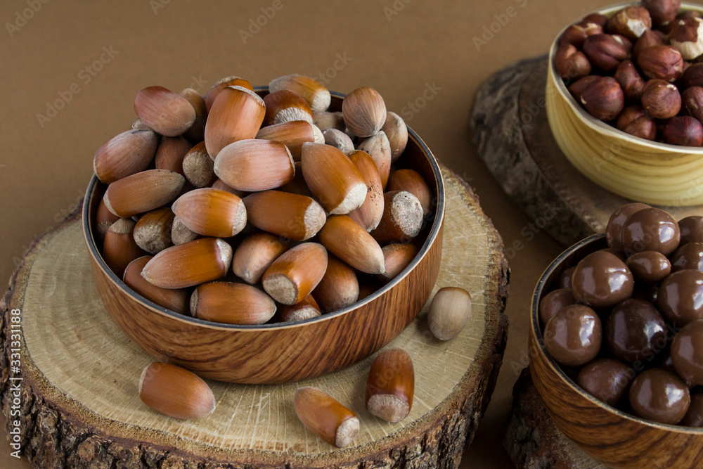 Turkish hazelnut from Black Sea Region and nut chocolates in bamboo bowls on the wooden boards. Turkish hazelnut from Black Sea Region and nut chocolates in bamboo bowls on the wooden boards.